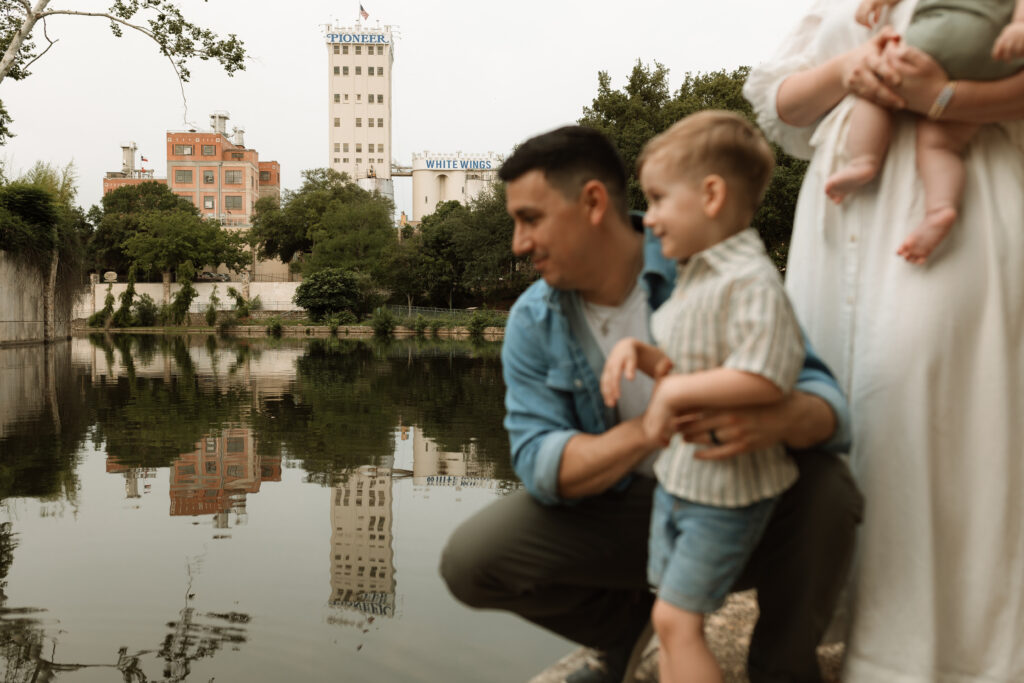 family looking at the San Antonio River with background in focus during sunrise photo session