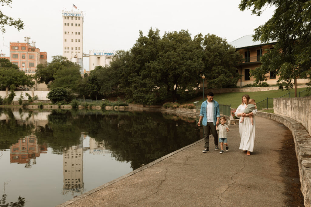 Family of four walking along San Antonio River around sunrise