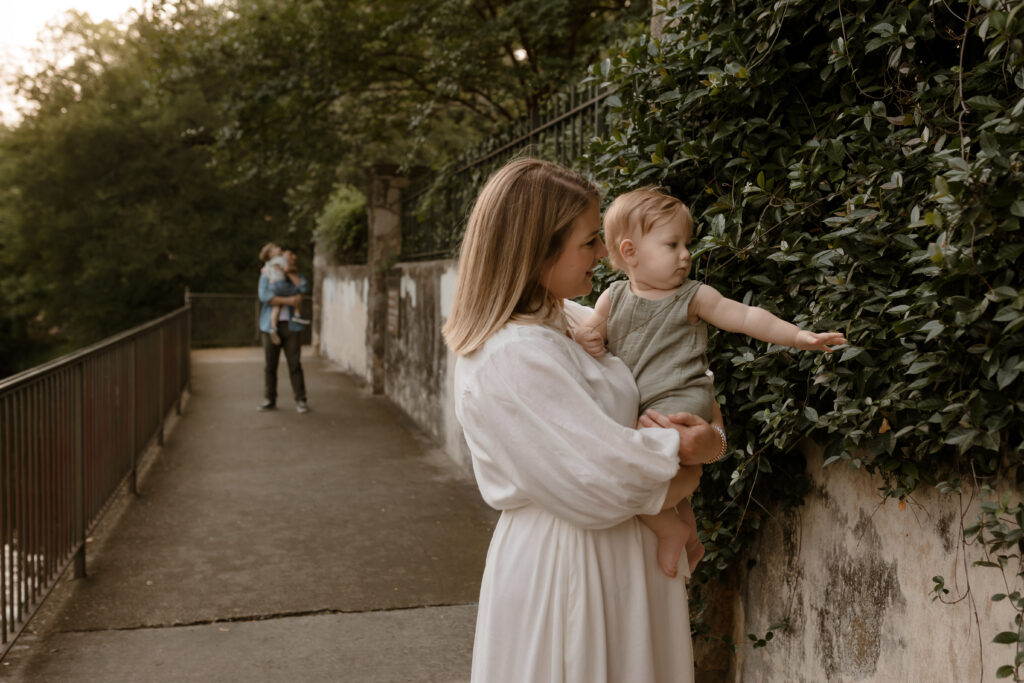 Mom holding baby boy with dad and son in the background during sunrise photo session