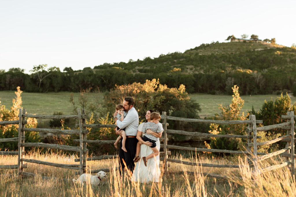 mom and dad holding kids by a fence