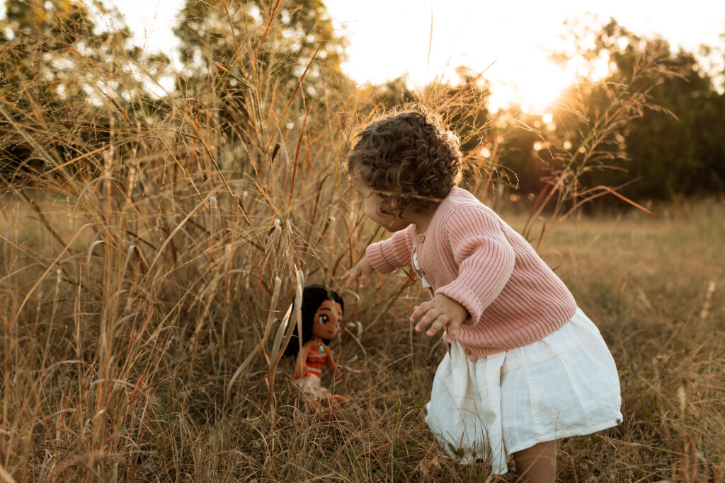 little girl playing with a doll during a family photo session