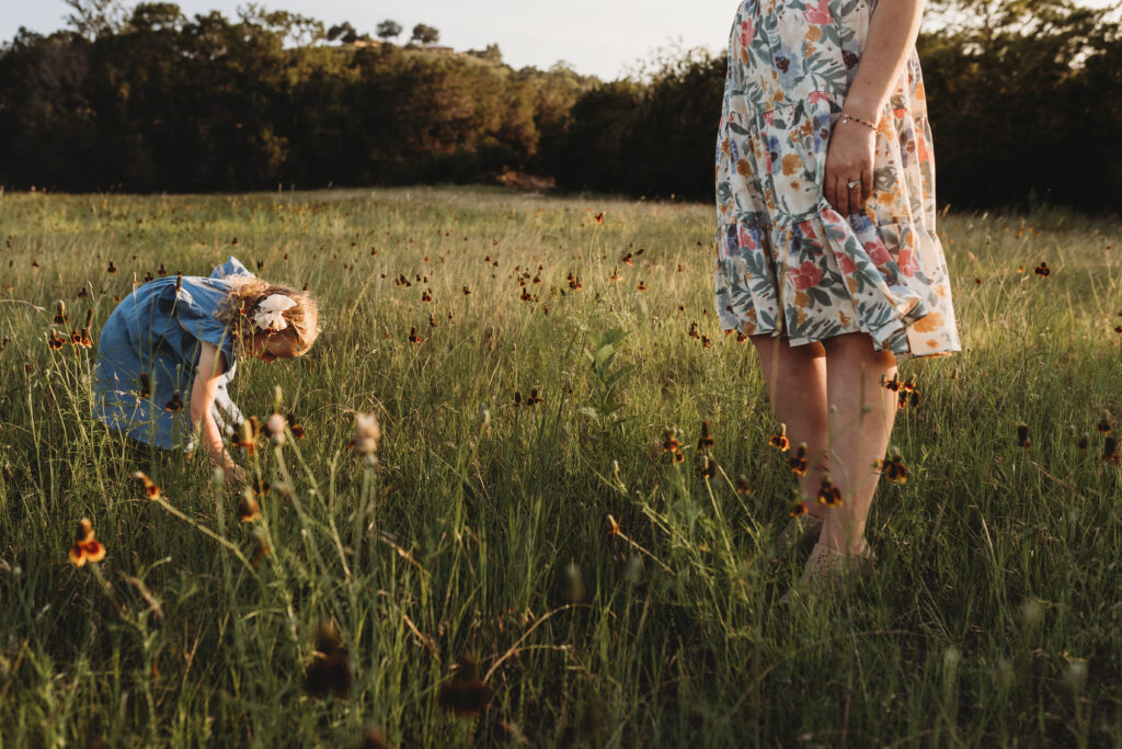 mom watching daughter pick flowers