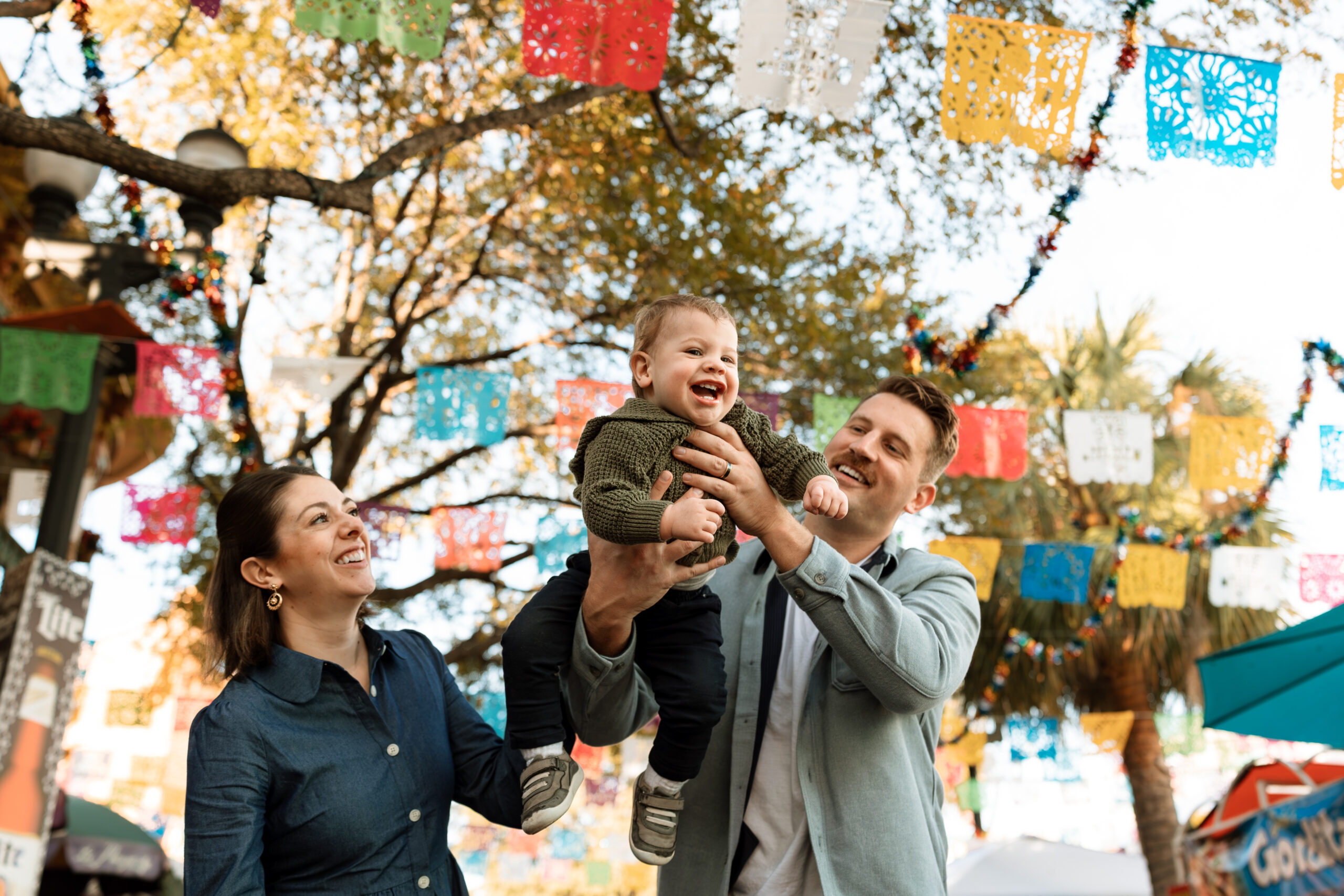 mom and dad swinging toddler boy in the air at Market Square