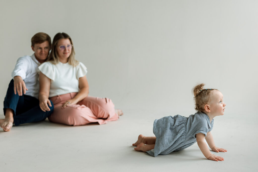 mom and dad watching baby girl crawl