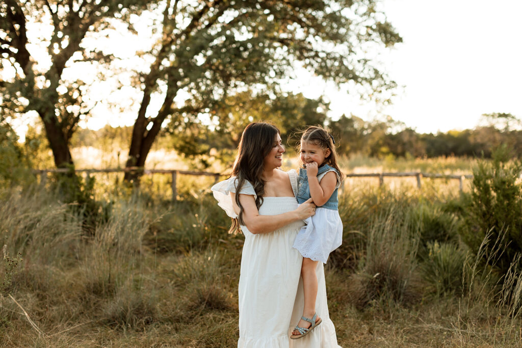 mom holding daughter in a park