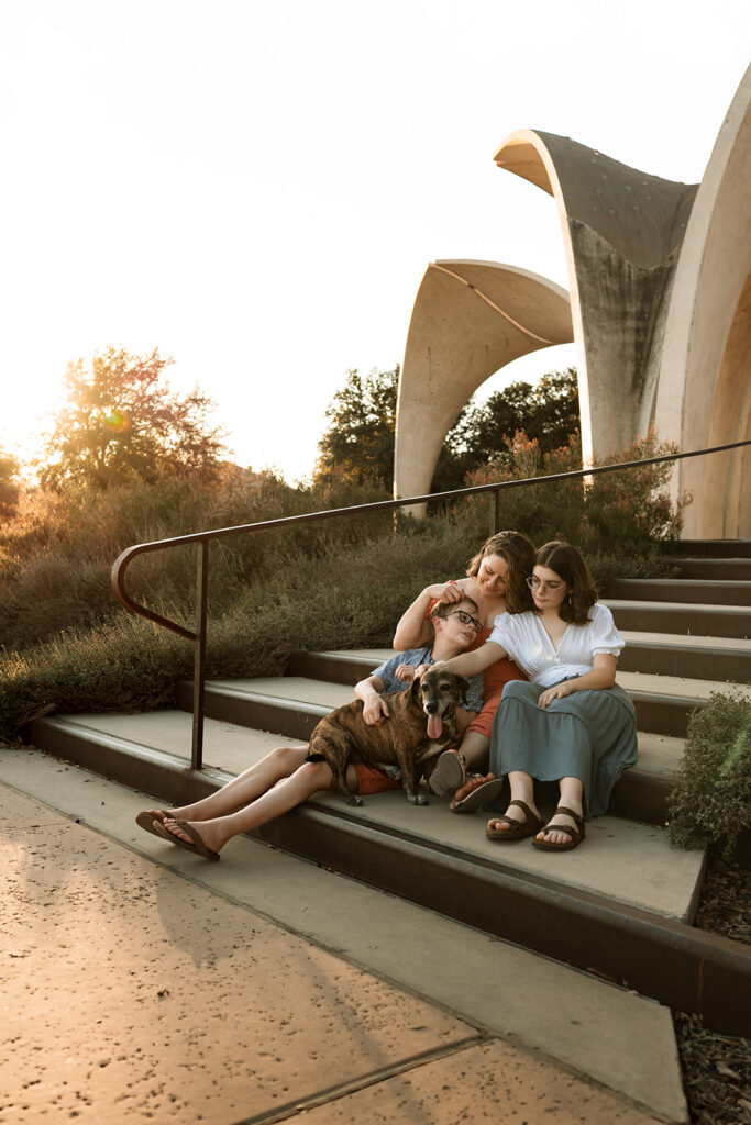 mother and teenage kids sitting on steps at a park