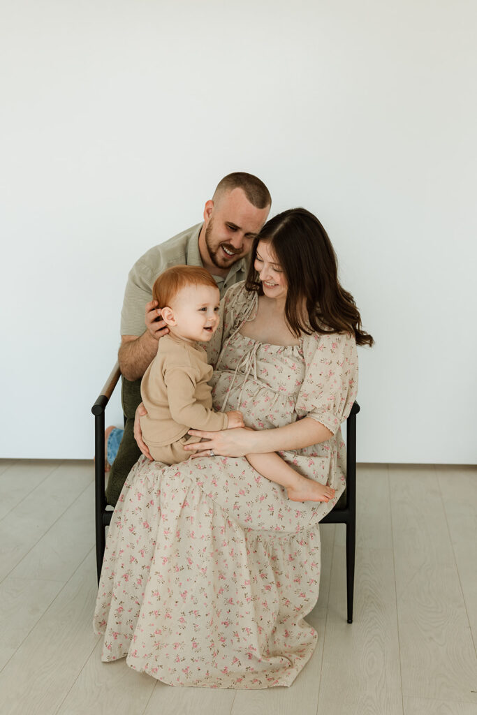 pregnant mom sitting with kid on her lap and husband behind them in the studio