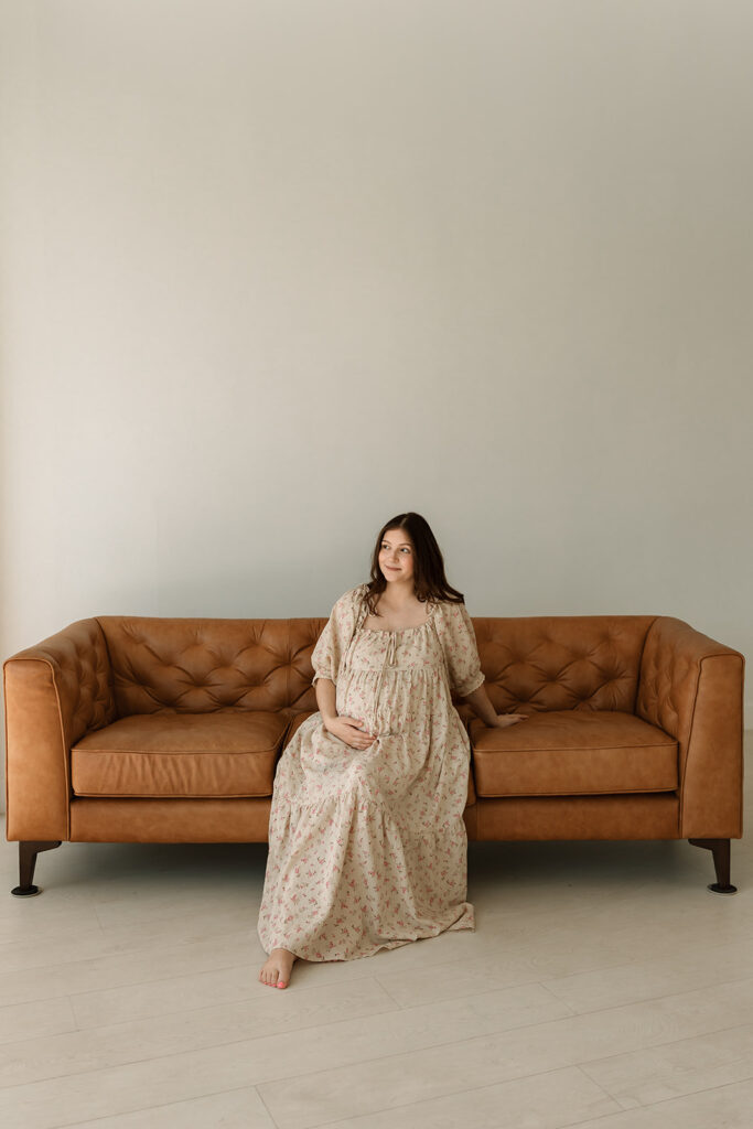 pregnant woman sitting on a couch in a studio