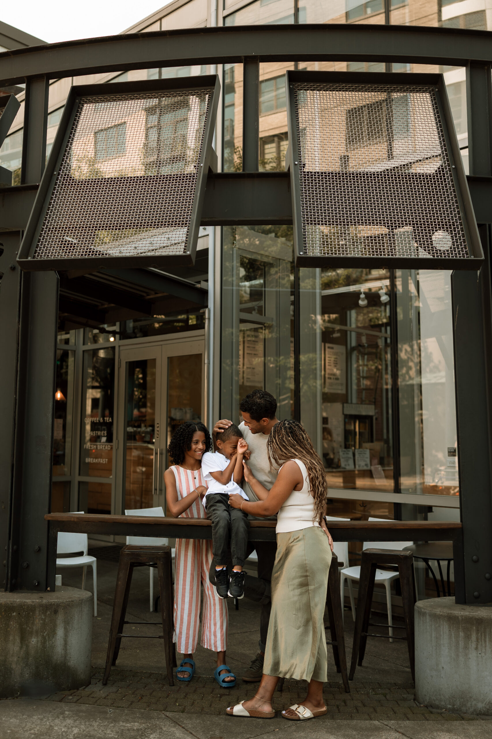 family of four standing at a bar top outside of a cafe downtown